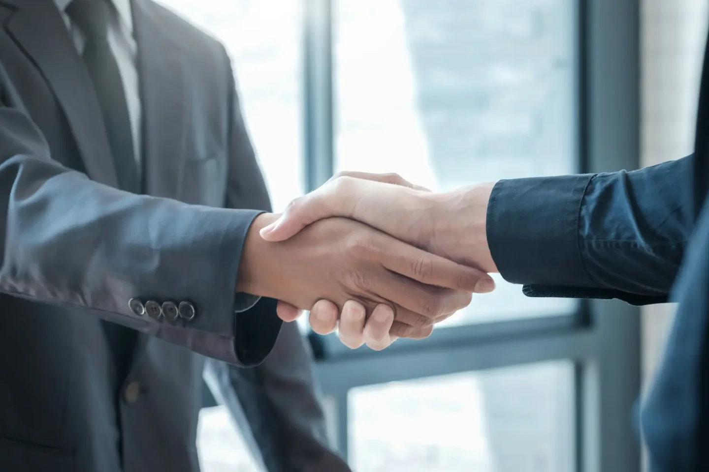 Two business partners shaking hands across a meeting table